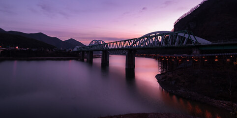 Beautiful and vibrant evening view of a bridge over the still waters of Namhan River in Danyang, South Korea. 