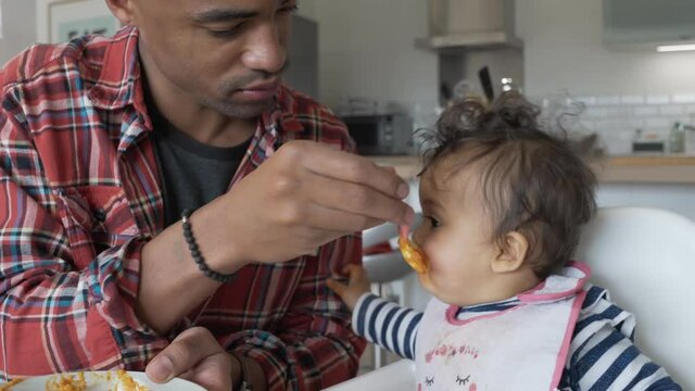 Daddy feeding 8-month-old baby girl 