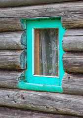 A green window in an old bathhouse made of round logs