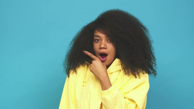 Young african american curly woman pointing to the side