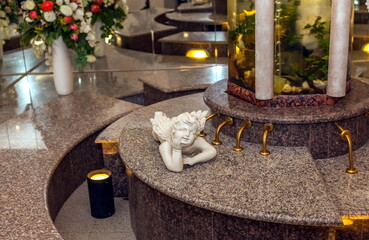 Interior details with a column-aquarium, angel figurine, vases with artificial flowers