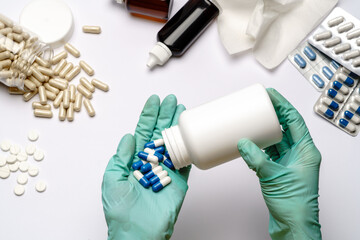 close up doctor hand in a latex glove holding capsules pills over light grey or white background with medical suppliements