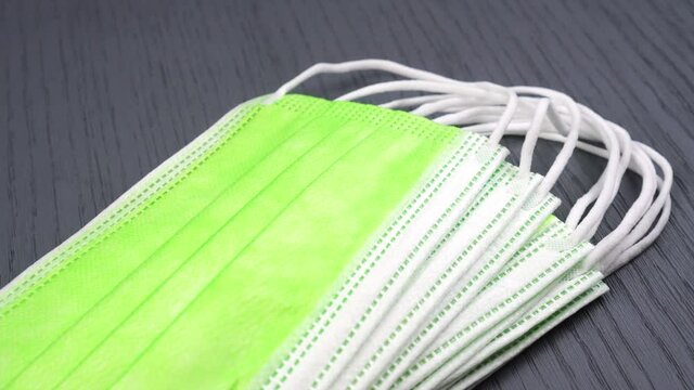 Bright green medical protective masks for children. A stack of hygienic stylish masks closeup on a gray wooden surface. Dolly Shot