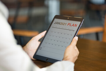 Close up of a businessman looking at new year 2021 planner on tablet screen to plan his business for coming new year.