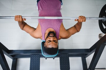 Weight lifter at the bench press lifting a barbell on an bench