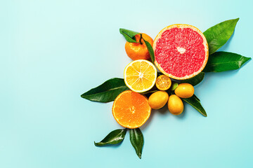 Creative background made of summer tropical fruits with leaves, grapefruit, orange, tangerine, lemon, kumquat on pastel blue background. Food concept. Flat lay, top view, copy space