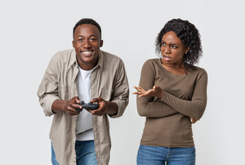 Man playing video games, woman is annoyed