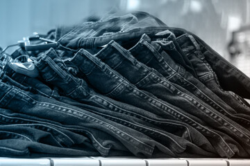 Fototapeta na wymiar Piles of jeans on a shelf in a store, close-up, selective focus, front view, tinted blue. Shopping clothes concept