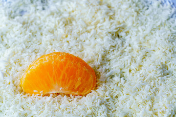 A juicy piece of tangerine lying in the snow. Vitamins in winter.