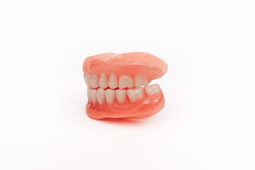 Full removable plastic denture of the jaws. Set of dentures on a white background. Two acrylic dentures. Upper and lower jaws with fake teeth. Dentures or false teeth, close-up. Copy space