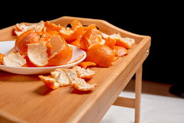 bed bamboo wooden tray with legs with the screen off. Concept of healthy food at night. Peel of tangerine and orange