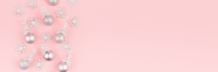 Festive bright new year background - pattern of glitter silver balls and snowflakes as decorative border on soft light pastel pink background, banner.