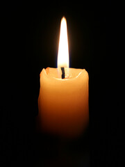 Burning candle on black background