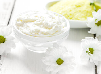 Obraz na płótnie Canvas homemade cosmetics with camomile herbs on white wooden background