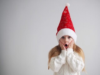 Christmas and happy New year. Portrait of a little girl holding her head with her hands, screaming with her mouth open and a crazy expression on her face. Surprised or shocked face. Space for text