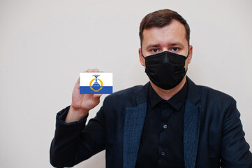 American man wear black formal and protect face mask, hold Orlando flag card isolated on white...