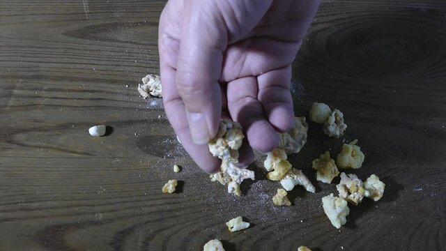 Hand picks up rock of crack cocaine drug from tabletop