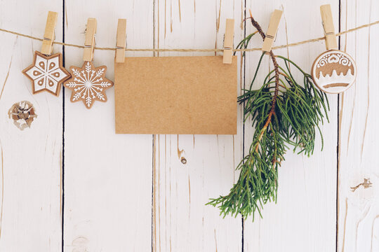 christmas decoration and blank paper card hanging on wood background.
