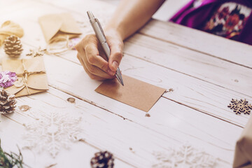Woman hand writing beautiful Christmas card at table