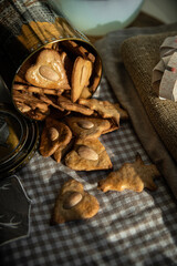 Metal box with homemade heart shaped  gingerbread cookies with almonds and Christmas ornaments on the windowsill. 
