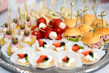 The buffet at the reception. Assortment of canapes on a table. Banquet service. Catering food, snacks with different types of cheese, ham, salami, prosciutto, shrimp, vegetables and fruits. Party Conc
