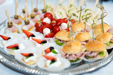 The buffet at the reception. Assortment of canapes on a table. Banquet service. Catering food, snacks with different types of cheese, ham, salami, prosciutto, shrimp, vegetables and fruits. Party Conc