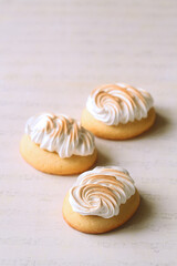 Obraz na płótnie Canvas Butter Cookies with Lemon Curd and topped with Burnt Italian Meringue, on a light beige background.