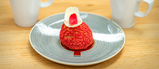 Luxury red dessert shu cake on a plate with a cup of latte on the table in a cafe