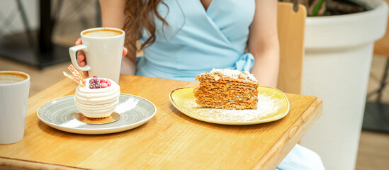 Sweet different pieces of cake on the plates at the table on a woman's background with a cup of coffee in a cafe