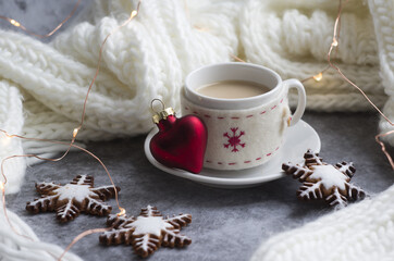 Obraz na płótnie Canvas beautiful winter composition: a white knitted scarf, a cup of coffee, gingerbread cookies in the form of snowflakes, a red glass heart. 
