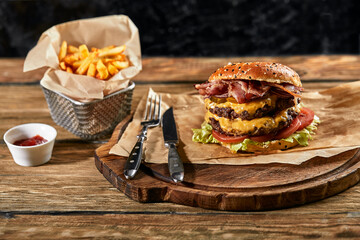 Set of hamburger beer and french fries. A standard set of drinks and food in the pub, beer and snacks. Dark background, fast food. Traditional american food.