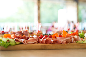 The buffet at the reception. Assortment of canapes on wooden board. Banquet service. Catering, snacks with different types of cheese and meat. Party Concept.