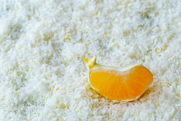 A juicy piece of tangerine lying in the snow. Vitamins in winter.