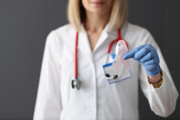 Doctor holding pink ribbon in his hand in rubber glove closeup