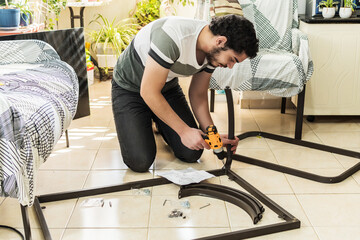 Casual young man assembling a table in the living room of his house.