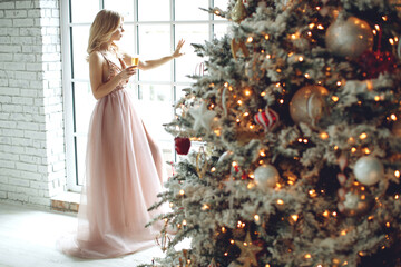 Woman in a beautiful dress, warm and cozy day in Christmas interior design, Christmas tree...