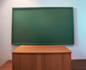 School desks and blank green blackboard in the classroom.