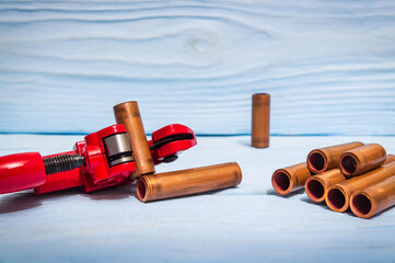 Red pipe cutter and copper pipes with connectors for plumbing repairs on blue wooden boards