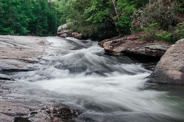 The mountain river flows among huge gray stones and trees with green foliage. Scenic highway 11 (eleven). Long Shoals Roadside State Park, SC, USA