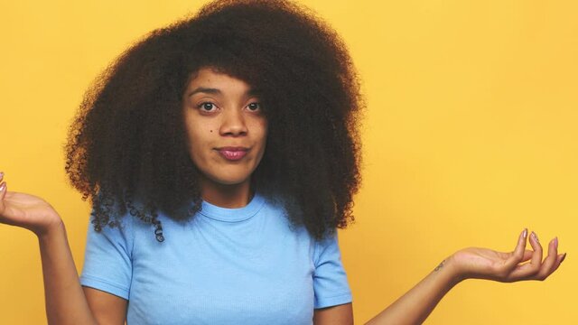 Young african american curly woman confused and doubtful shrugging shoulders to hold a copy space