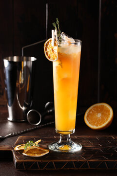 Alcoholic cocktail. Special hurricane. Orange drink made from rum, pineapple, passion fruit puree, orange almonds and grapefruit in a transparent glass on a wooden table. Bar menu. Background image