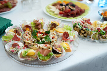 The buffet at the reception. Assortment of canapes on a table. Banquet service. Catering food, snacks with different types of cheese, ham, salami, prosciutto, shrimp, vegetables and fruits. 