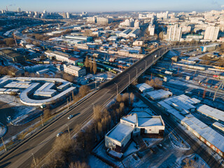 winter aerial of modern city with tall buildings, road moving cars along streets