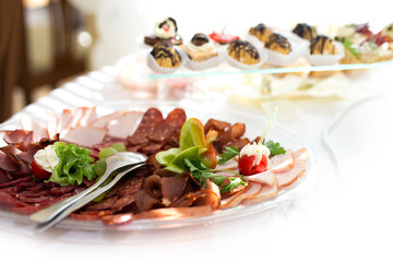 The buffet at the reception. Assortment of canapes on a table. Banquet service. Catering food, snacks with different types of cheese, ham, salami, prosciutto, shrimp, vegetables and fruits. 
