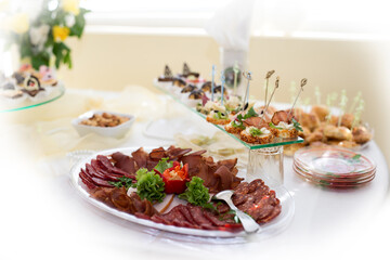 The buffet at the reception. Assortment of canapes on a table. Banquet service. Catering food, snacks with different types of cheese, ham, salami, prosciutto, shrimp, vegetables and fruits. 