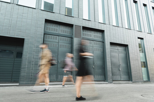 Motion Blur Of People Walking On Street Near Grey Building