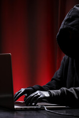 International hacker in black pullover and black mask trying to hack government on a black and red background. Cyber crime . Cyber security.