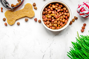 dry dog food in bowl on stone background top view