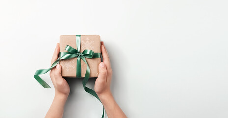 Gift box in a beautiful festive paper packaging in hands blue background