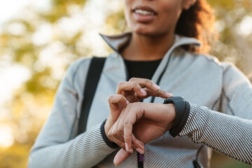 Happy african american sportswoman using smartwatch in park